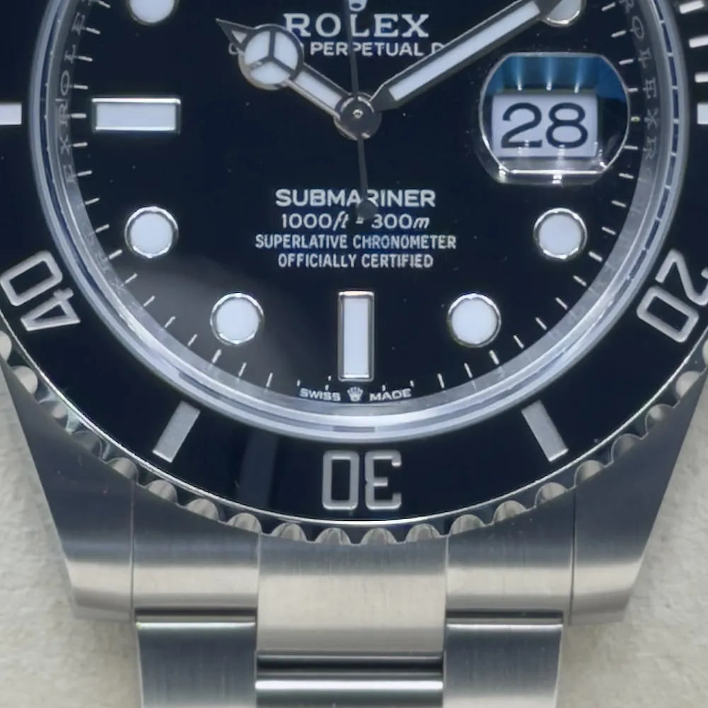 Detailaufnahme einer Rolex Submariner: unteres Zifferblatt, Rehaut mit Gravur, Lünette und Gehäuse